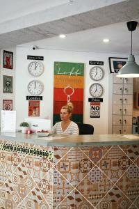 a woman sitting at a counter with clocks on the wall at LOFT APART & HOSTAL Group in Lloret de Mar