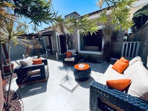 eine Terrasse mit einem Sofa, Stühlen und Palmen in der Unterkunft Casa de férias São josé Maragogi in São José da Coroa Grande