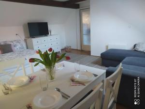 a dining table with two plates and a vase of flowers on it at Dóra Apartman in Balatonszárszó