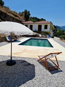 una silla y una sombrilla junto a la piscina en Quinta do Fojo Valonguinho, Barrô, en Barrô