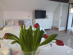 a vase with flowers on a table in a bedroom at Dóra Apartman in Balatonszárszó +10 photos
