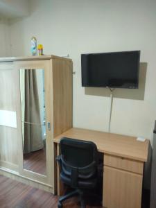 a desk with a chair and a television on a wall at Puri Orchard Apartment in Jakarta