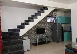 ein Wohnzimmer mit einer Treppe und einem TV in der Unterkunft Bluebeli Mountain Villa By Holiday Villass in Mahabaleshwar