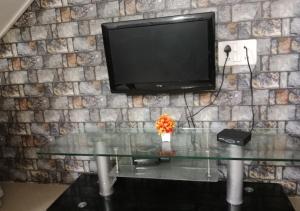 einen TV an einer Steinmauer mit einem Glastisch in der Unterkunft Bluebeli Mountain Villa By Holiday Villass in Mahabaleshwar