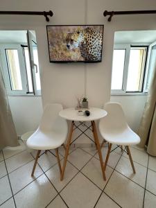 a table and four chairs in a room with a wall at Valente Rooms Kythira in Kythira