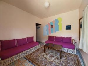 uma sala de estar com sofás roxos e uma mesa em Caiat Lounge Refuge em Taghzoute