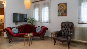 un soggiorno con 2 sedie e un divano rosso di Postmans Apartment Under Meteora a Kalabaka