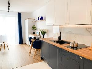 a kitchen with white cabinets and a wooden counter top at Healthy Life Apartment in Warsaw