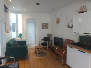 a living room with a green couch and a kitchen at Maison avec 4 chambres au centre de st Valéry in Saint-Valéry-sur-Somme