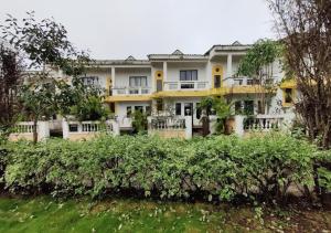 ein großes weißes Gebäude mit Bäumen davor in der Unterkunft Bluebeli Mountain Villa By Holiday Villass in Mahabaleshwar