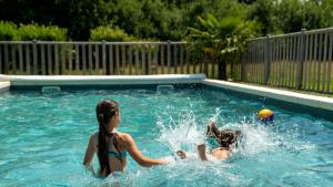 twee meisjes spelen met een bal in een zwembad bij Village Toue du Domaine des Demoiselles in Chassenard