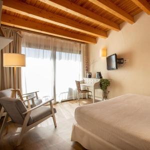 um quarto com uma cama, uma secretária e uma televisão em Hotel Boutique Niu de Sol - Designed for Adults em Palau-Saverdera
