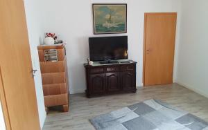 a room with a flat screen tv sitting on a wooden cabinet at Am Luhestrand in Luhdorf