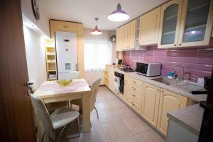 a small kitchen with a table and chairs and purple tiles at Camarad’s house - lovely apartment in Alba Iulia in Alba Iulia