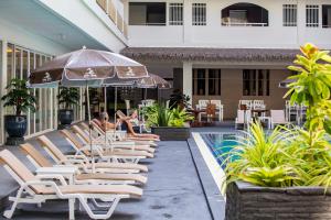 a group of lounge chairs and an umbrella next to a pool at Sabai Sabana in Pattaya