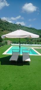 um guarda-sol branco e duas cadeiras ao lado de uma piscina em B&B Badde Tale em Ossi