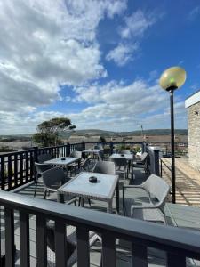 a patio with tables and chairs on a balcony at Jone’s Cove in Swanage