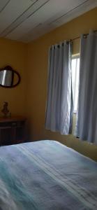 sypialnia z łóżkiem i oknem z białymi zasłonami w obiekcie Teresópolis Hostel w mieście Teresópolis