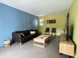 a living room with a black couch and a table at La Passerelle Grande maison avec Piscine chauffée in Rivedoux-Plage