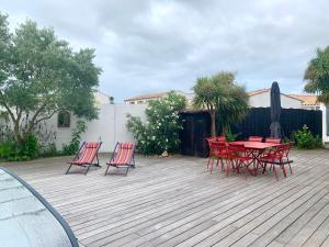 un groupe de chaises rouges et une table sur une terrasse dans l'établissement La Passerelle Grande maison avec Piscine chauffée, à Rivedoux-Plage