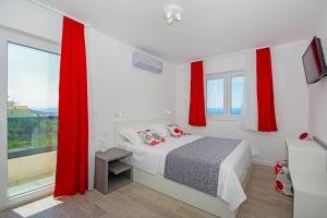 a bedroom with red curtains and a bed and a window at Holiday Home Ferias in Makarska