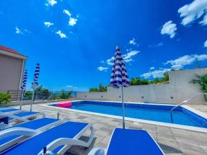 a swimming pool with blue tables and chairs next to it at Holiday Home Ferias in Makarska