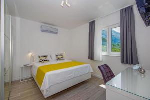 a white bedroom with a bed and a glass table at Holiday Home Ferias in Makarska