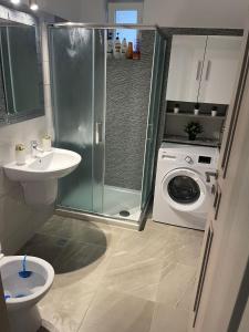 een badkamer met een douche, een wastafel en een wasmachine bij HOME NAS Bragadiru in Bragadiru