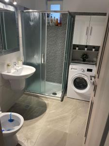 a bathroom with a shower sink and a washing machine at HOME NAS Bragadiru in Bragadiru