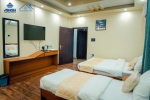 a hotel room with two beds and a flat screen tv at Hotel Happy Home in Bhairāhawā