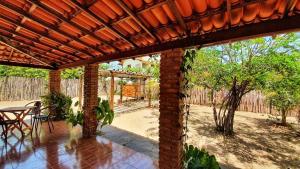 a brick patio with a table and a wooden pergola at Casa Barra Jucá - Barra Grande Piauí in Barra Grande