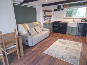 uma sala de estar com um sofá e uma cozinha em The Loft at Foxglove Lodge 