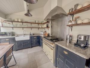 a kitchen with blue cabinets and a stove top oven at Old School House - Luxury 4 bed holiday home near Norwich, Norfolk in Lingwood