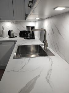 a kitchen with a sink in a white counter top at Apartment Upseeritie in Kouvola