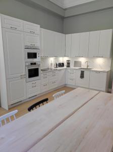 a kitchen with white cabinets and a large wooden table at Apartment Upseeritie in Kouvola