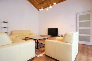 a living room with two white couches and a tv at Mati Apartments Prishtina in Prishtinë