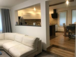 a living room with a white couch and a kitchen at Penzion - VILA VERI 1 in Ostrava