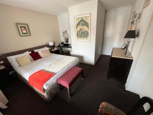a hotel room with a bed and a red chair at Hôtel Ursula in Cambo-les-Bains