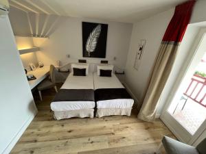 1 dormitorio con cama, escritorio y ventana en Hôtel Ursula, en Cambo-les-Bains