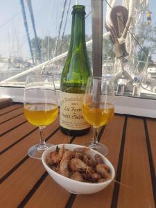 een kom champignons en twee glazen wijn op een tafel bij Voilier de charme en acajou. in Ouistreham