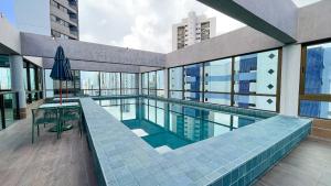 een zwembad met een tafel en een parasol in een gebouw bij Rooftop #1308 - Estúdio em Boa Viagem by Carpediem in Recife