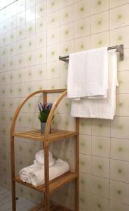 ein Badezimmer mit einem Handtuchhalter und einem Regal mit Handtüchern in der Unterkunft Casa do Limoeiro in Albufeira