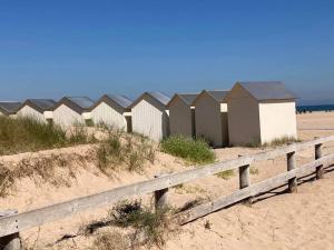 uma fileira de cabanas de praia numa praia arenosa em Voilier de charme en acajou. em Ouistreham