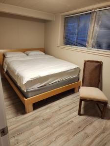 a bedroom with a bed and a chair in it at Economical Homestay in Burnaby