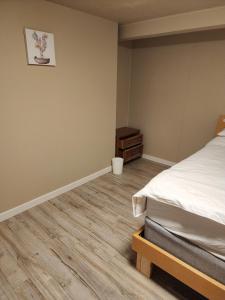 1 dormitorio con 1 cama y suelo de madera en Economical Homestay en Burnaby