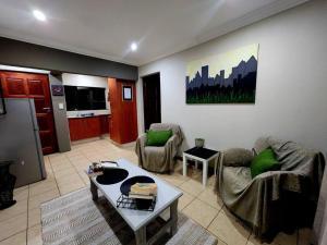 a living room with two chairs and a table at Lily Rest Garden Cottage in Pretoria