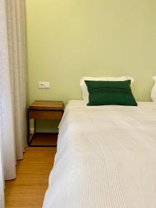 una camera con un letto bianco e un cuscino verde di Misericórdia Garden Homes a Vila do Conde