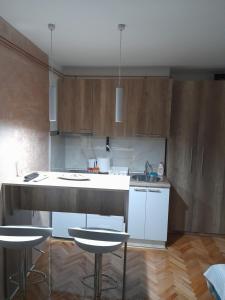a kitchen with a counter and two stools in it at Holiday apartament three in Niš +13 photos