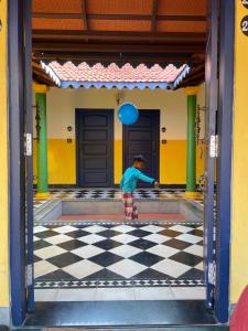 un jeune garçon jouant sur un sol en damier dans un bâtiment dans l'établissement Marutham Village Resort, à Mahabalipuram