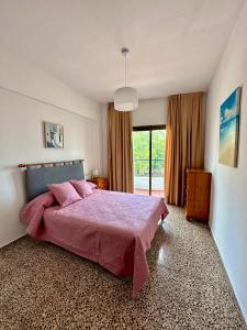 a bedroom with a pink bed and a large window at Hostal y Apartamentos Santa Eulalia in Santa Eularia des Riu